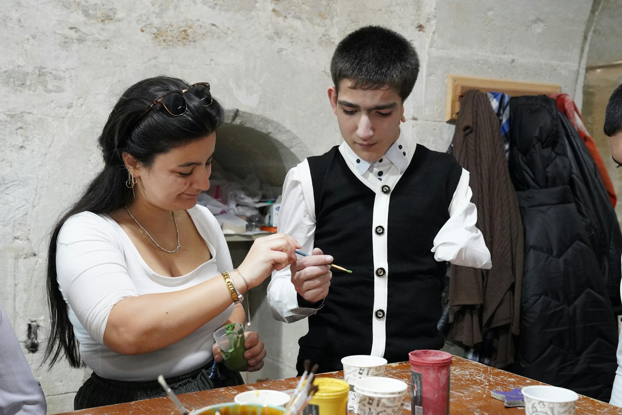 A young man and woman engaged in an art lesson, focusing on creativity and inclusion.