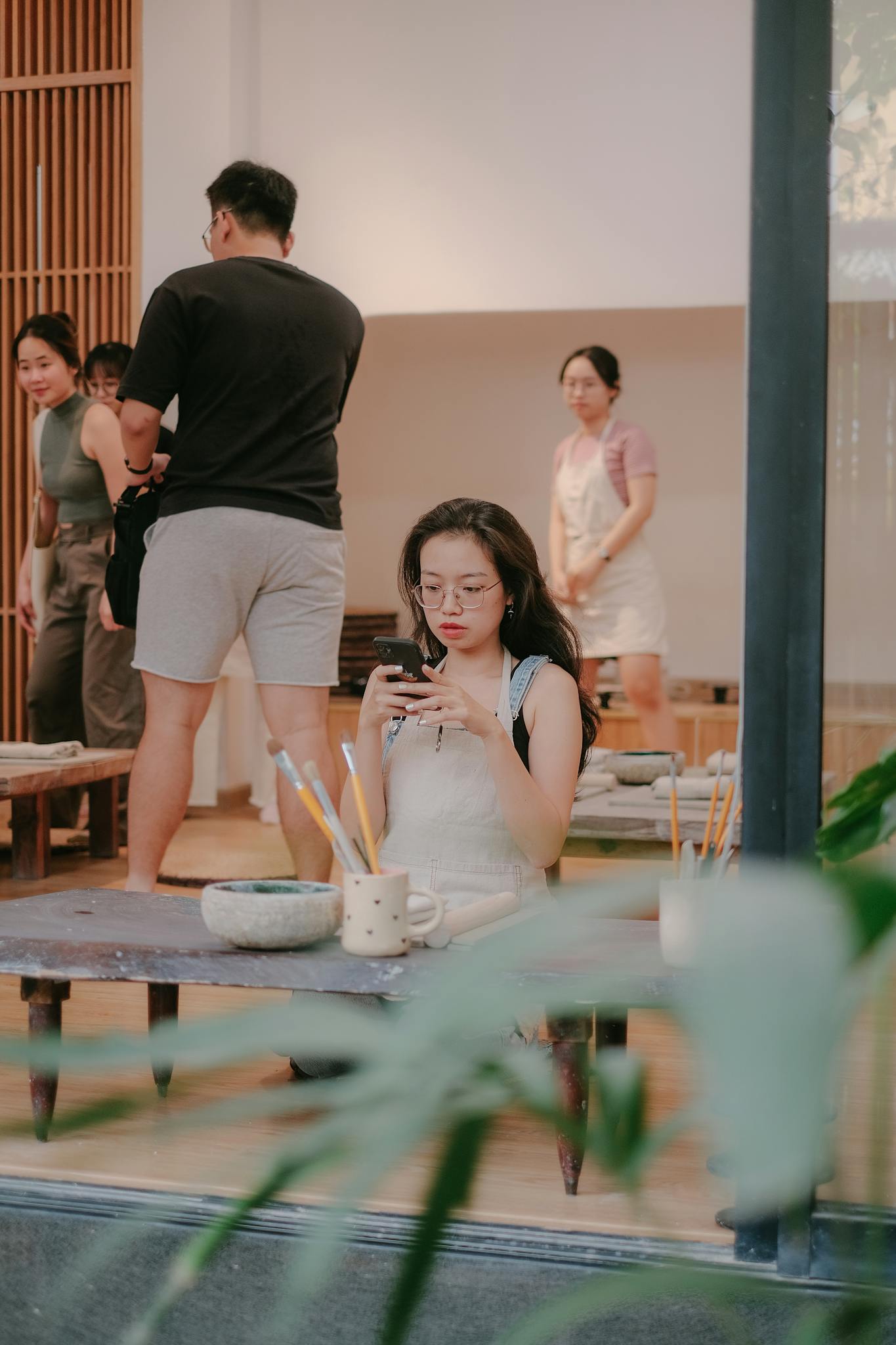 Art class with a teacher and students interacting, surrounded by art materials.