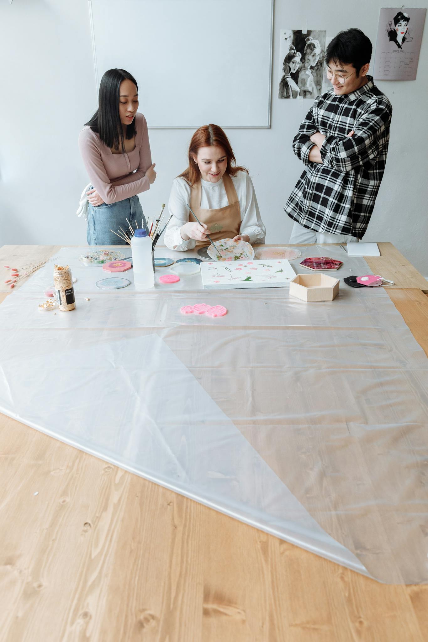 Art instructor demonstrating painting techniques to adult students in a classroom.